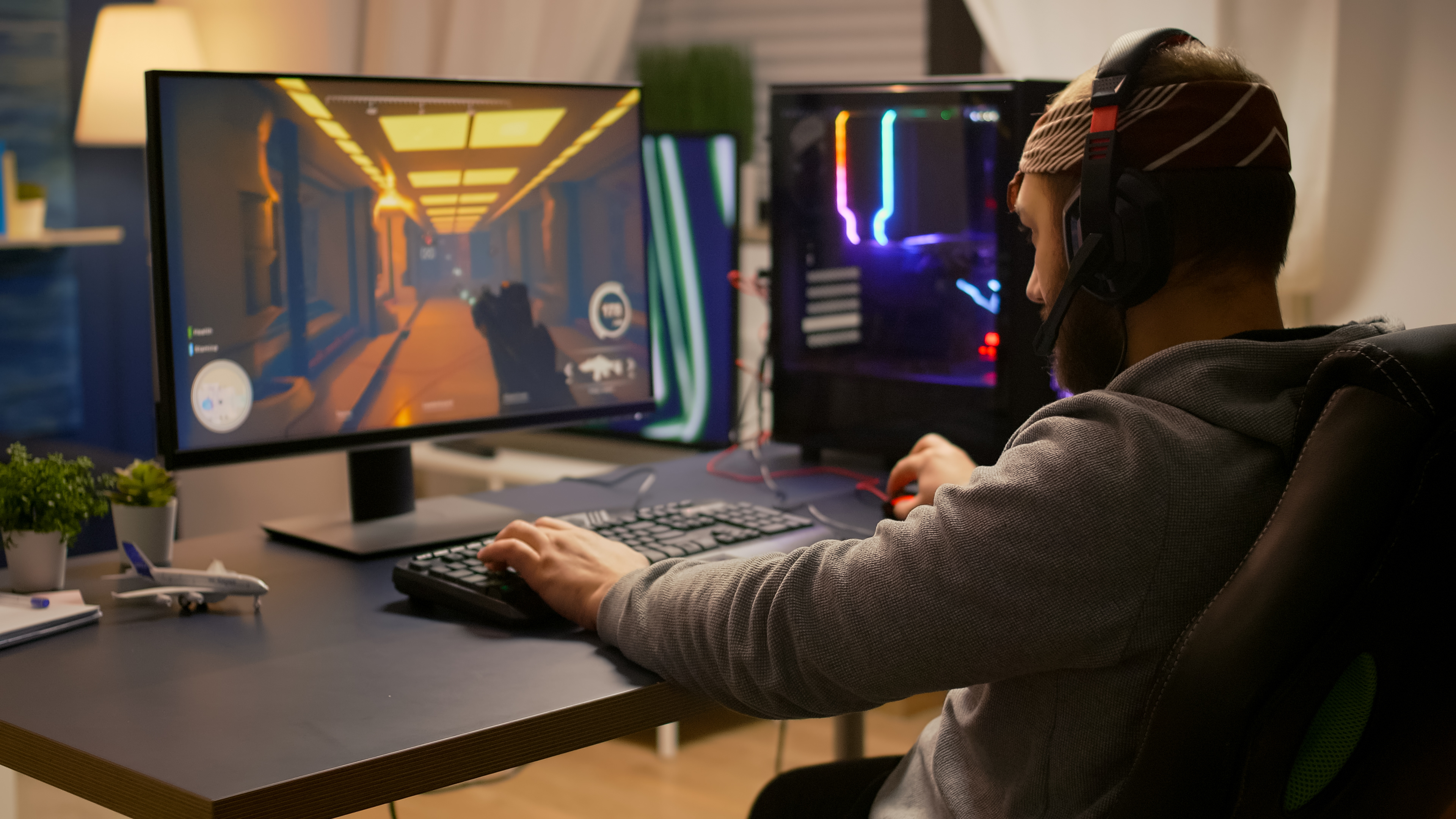 Personne assise à un bureau jouant à un jeu vidéo de tir à la première personne