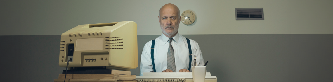 A person working at a desk using a vintage computer monitor and keyboard.